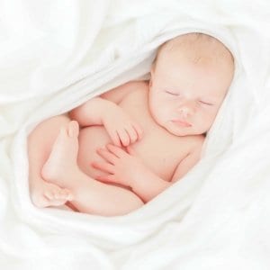 Sleeping baby wrapped in white blanket