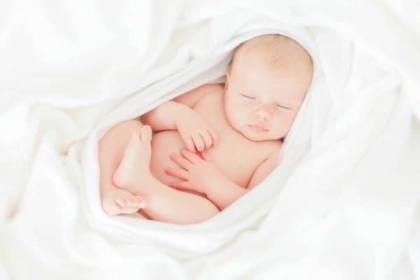 Sleeping baby wrapped in white blanket