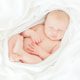 Sleeping baby wrapped in white blanket