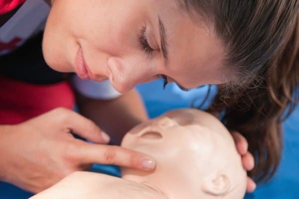 Woman practicing CPR on infant mannequin